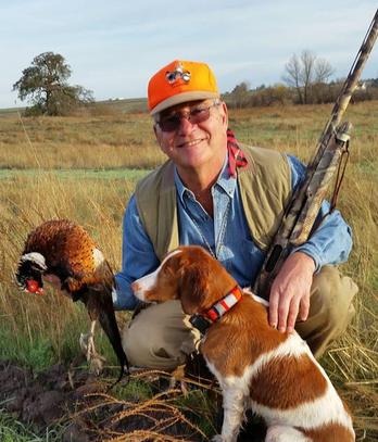 A hunter with a pheasant and his Brittany spaniel