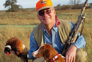 A hunter with a pheasant and his dog